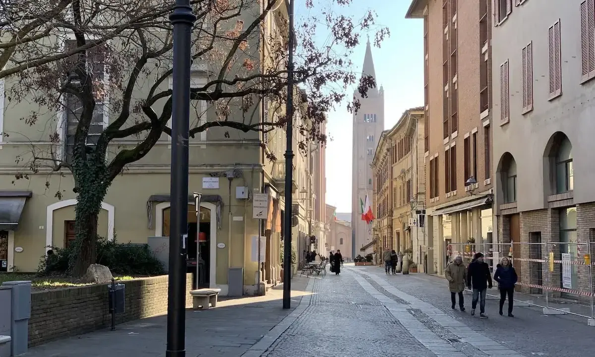 Spacerem po urokliwej uliczce w Forlì, Włochy. W oddali widać wieżę kościelną i włoską flagę.
