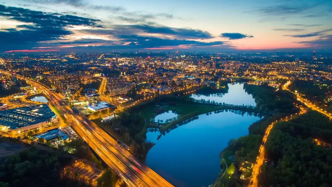 Wieczorny widok na rozświetlone miasto i trzy stawy w Dolinie Trzech Stawów w Katowicach.