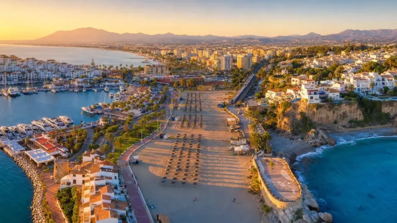 Widok na port jachtowy i plażę w słoneczny dzień. Idealne miejsce, by odkryć, co warto zobaczyć na Costa del Sol.