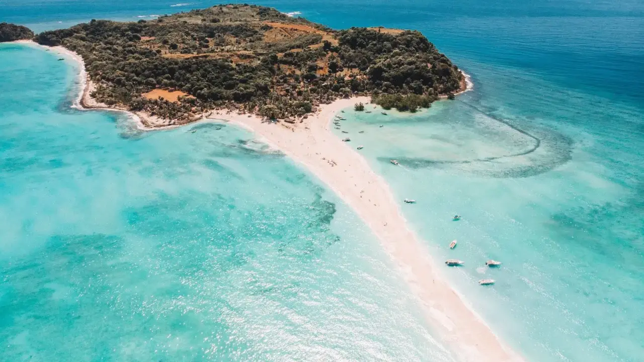 Rajska plaża na Nosy Be, z turkusową wodą, piaszczystym cyplem i łodziami.