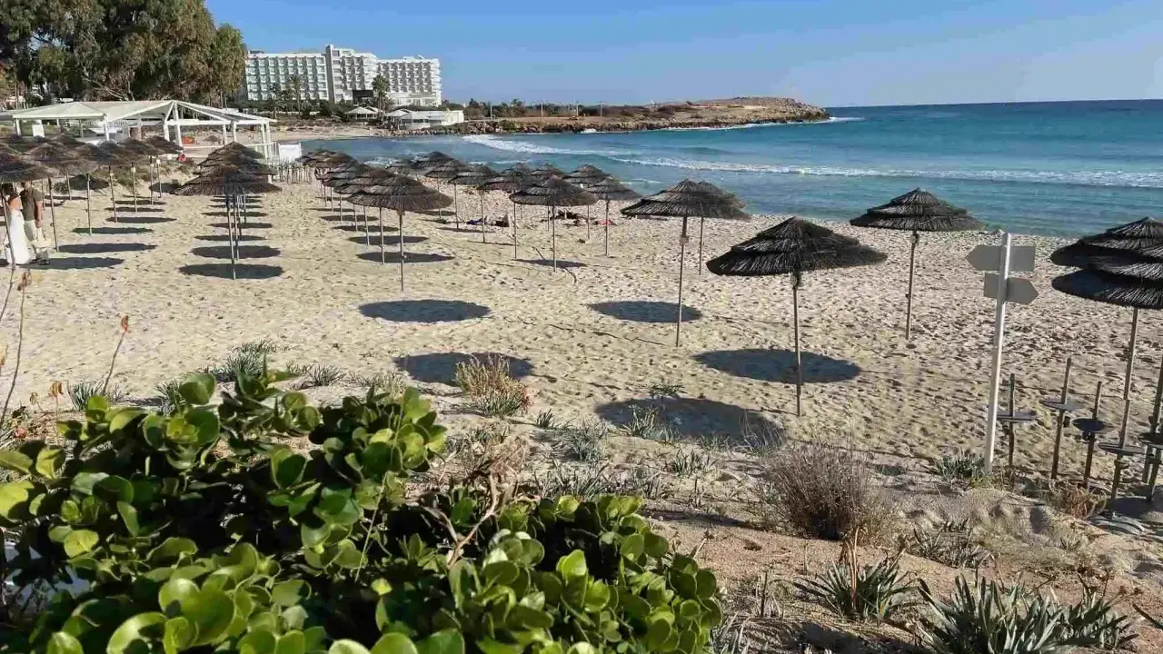 Plaże Cypru Północnego z rzędami parasoli i hotelami w tle.