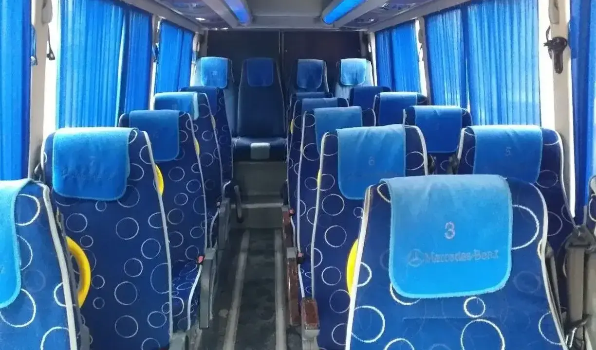Wygodne siedzenia w autobusie, idealne na transport między Tiraną a Durrës. Błękitne zasłony i wzorzyste obicia dodają uroku.