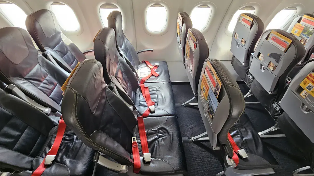 Puste fotele w samolocie Pegasus Airlines, gotowe na odprawę pasażerów. Czerwone pasy bezpieczeństwa czekają.