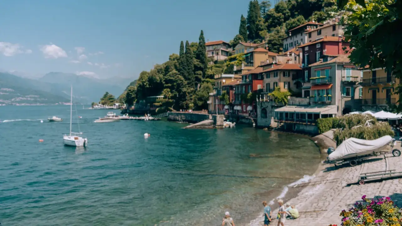 Urokliwa plaża w Bergamo, z kolorowymi domkami na wzgórzu, łodziami na wodzie i dziećmi bawiącymi się nad brzegiem.