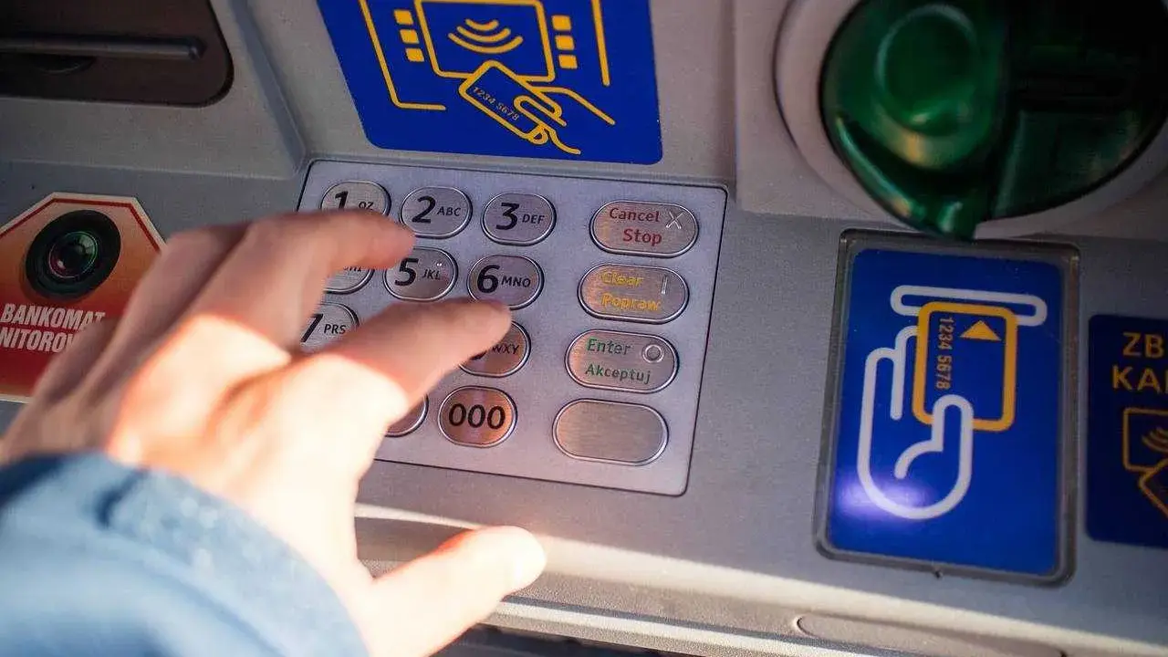 Dłoń wpisuje PIN na bankomacie w Turcji. Szukaj bankomatów bez prowizji, by oszczędzić na wakacjach.