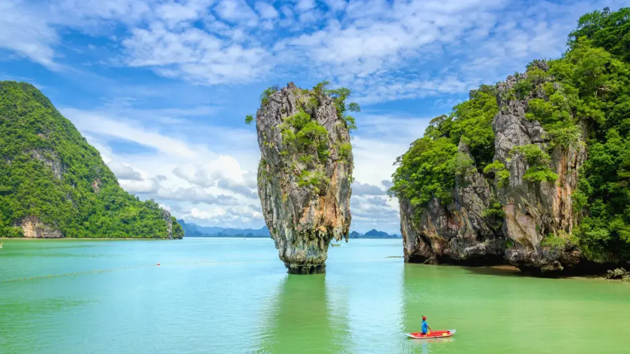 Wyspa Phuket, Tajlandia: samotna skała wyrasta z turkusowej wody, a kajakarz podziwia krajobraz.