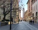 Spacerem po urokliwej uliczce w Forlì, Włochy. W oddali widać wieżę kościelną i włoską flagę.
