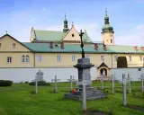 Cmentarz przy klasztorze w Czerniej. W tle żółty budynek z zielonym dachem i wieżą.