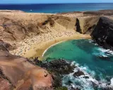 Rajska plaża z turkusową wodą i ludźmi opalającymi się na piasku. To idealne miejsce, co zobaczyć na Lanzarote, by poczuć słońce i odpocząć.