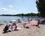 Słoneczny dzień nad **jaworznem jeziorem**. Ludzie odpoczywają na plaży, kąpią się i opalają.