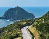 Malownicza droga wije się pośród zielonych wzgórz na Okinawie w Japonii, z widokiem na spokojne morze i skalistą wyspę.