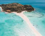 Rajska plaża na Nosy Be, z turkusową wodą, piaszczystym cyplem i łodziami.