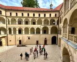 Dziedziniec zamku Ojcowie z arkadowymi krużgankami, gdzie spacerują turyści.