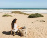 Dziewczyna pije herbatę na plaży, delektując się widokiem na morze w Tunezji.