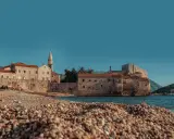 Kamienista plaża w Budvie, z widokiem na starówkę i morze. Idealne miejsce, by zastanowić się, jak dojechać z Podgoricy do Budvy.