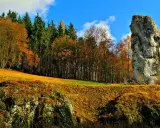 Jesienna trasa Maczugi Herkulesa. Wysoka skała góruje nad złotymi polami i kolorowym lasem.
