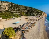 Piękne albania plaże z rzędami leżaków i parasoli, skaliste zbocze i turkusowe morze.