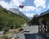 Wspaniałe widoki w Chile! Flaga powiewa nad chatką, a w tle majestatyczne góry. Idealne miejsce, by zobaczyć cuda natury.