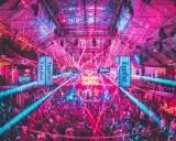 Tłum ludzi tańczy w rytm muzyki pod neonowymi światłami i laserami. To niezapomniane ibiza imprezy w klubie pełnym energii.