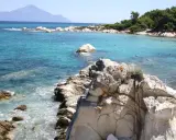 Piękne, turkusowe morze i skaliste wybrzeże. Ludzie kąpią się i opalają na plaży. To idealne chalkidiki atrakcje dla każdego.