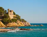 Zamek na klifie nad turkusowym morzem, malownicze costa brava plaże.