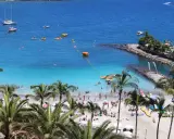 Słoneczne gran canaria plaże pełne ludzi, łodzi i palm. Błękitna woda zaprasza do kąpieli i wodnych zabaw.