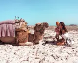 Kobieta z dzieckiem na plaży w Tunezji, obok wielbłąd. Niezapomniane tunezja atrakcje.