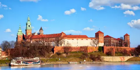 Zamek Królewski na Wawelu, z zielonymi wieżami i czerwonymi dachami, góruje nad Wisłą. Ciekawostki o jego historii czekają na odkrycie.