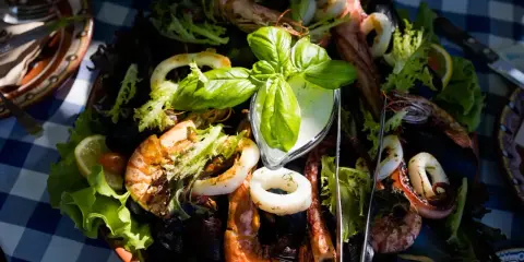 Pyszne owoce morza z sałatką i sosem, serwowane na talerzu w jednej z restauracji na słonecznym brzegu.