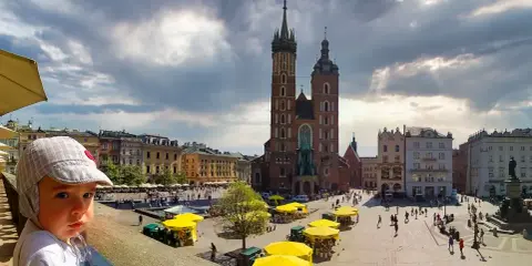 Dziecko na tle Rynku Głównego w Krakowie. To jedno z fajnych miejsc w Krakowie dla młodzieży, pełne życia i zabytków.