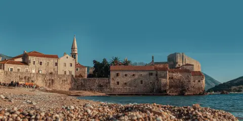 Kamienista plaża w Budvie, z widokiem na starówkę i morze. Idealne miejsce, by zastanowić się, jak dojechać z Podgoricy do Budvy.