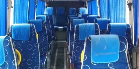Wygodne siedzenia w autobusie, idealne na transport między Tiraną a Durrës. Błękitne zasłony i wzorzyste obicia dodają uroku.
