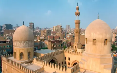 Dwie kopuły i minaret meczetu na tle zabudowań Kairu. Idealne miejsce na samodzielną podróż, by odkryć Egipt na własną rękę.