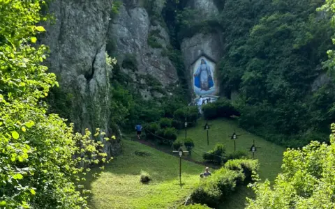 Malownicza dolinka mnikowska z kapliczką Matki Boskiej w skale. Ścieżka prowadzi przez zieloną łąkę, ozdobioną krzyżami.
