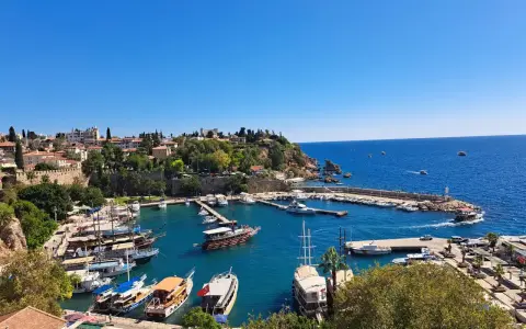 Widok na port w Antalyi, gdzie cumują liczne łodzie i jachty. W tle widać miasto i błękitne morze. Idealne miejsce, by zobaczyć, co oferuje Antalya.