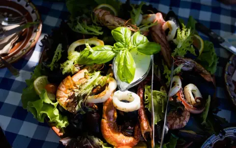Pyszne owoce morza z sałatką i sosem, serwowane na talerzu w jednej z restauracji na słonecznym brzegu.