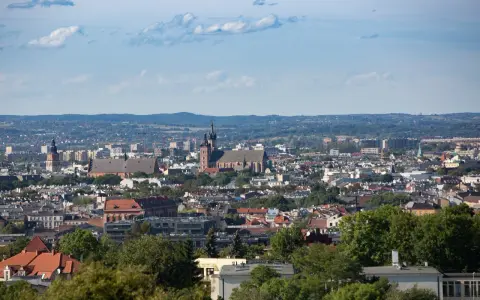 Widok na Kraków z punktu widokowego. W oddali widać kościół Mariacki i Wawel, a bliżej zabudowania miejskie i zieleń.
