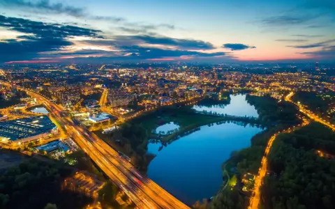 Wieczorny widok na rozświetlone miasto i trzy stawy w Dolinie Trzech Stawów w Katowicach.