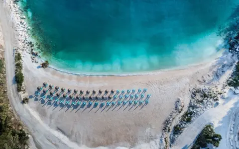 Rajska plaża na Thassos z turkusową wodą i rzędami leżaków. Idealne miejsce na relaks i podziwianie pięknych widoków.