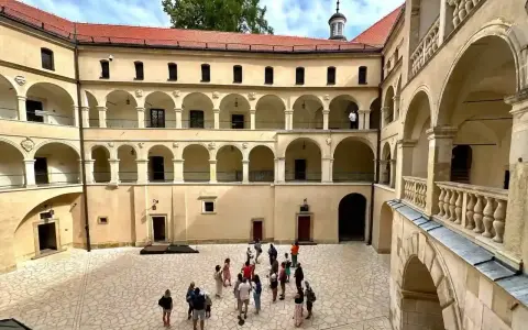 Dziedziniec zamku Ojcowie z arkadowymi krużgankami, gdzie spacerują turyści.