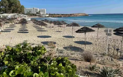 Plaże Cypru Północnego z rzędami parasoli i hotelami w tle.