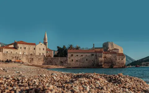 Kamienista plaża w Budvie, z widokiem na starówkę i morze. Idealne miejsce, by zastanowić się, jak dojechać z Podgoricy do Budvy.
