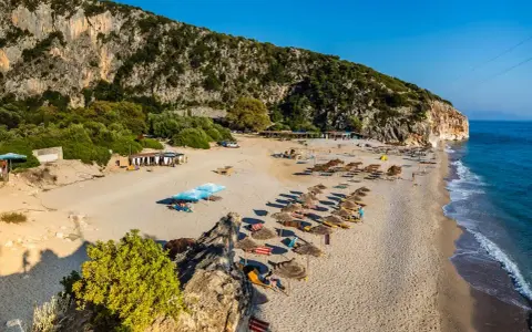 Piękne albania plaże z rzędami leżaków i parasoli, skaliste zbocze i turkusowe morze.