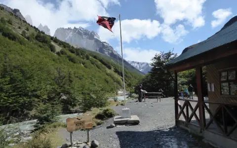 Wspaniałe widoki w Chile! Flaga powiewa nad chatką, a w tle majestatyczne góry. Idealne miejsce, by zobaczyć cuda natury.