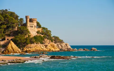 Zamek na klifie nad turkusowym morzem, malownicze costa brava plaże.