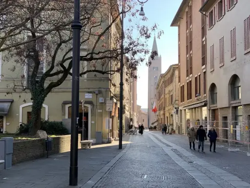 Spacerem po urokliwej uliczce w Forlì, Włochy. W oddali widać wieżę kościelną i włoską flagę.