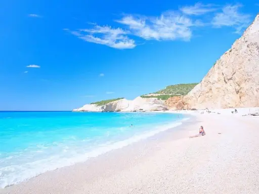 Rajskie lefkada plaże z turkusową wodą i białym piaskiem. Kobieta odpoczywa na plaży, podziwiając widok.