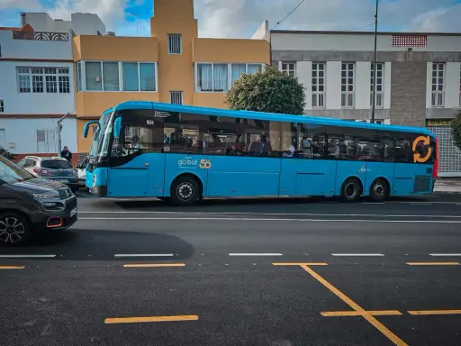 Błękitny autobus firmy Global 50, jeden z wielu gran canaria autobusy, jedzie ulicą.