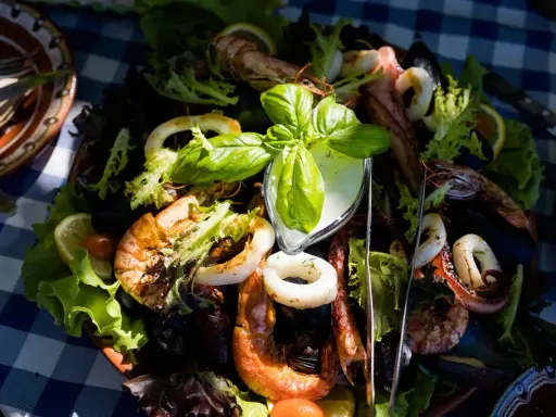 Pyszne owoce morza z sałatką i sosem, serwowane na talerzu w jednej z restauracji na słonecznym brzegu.