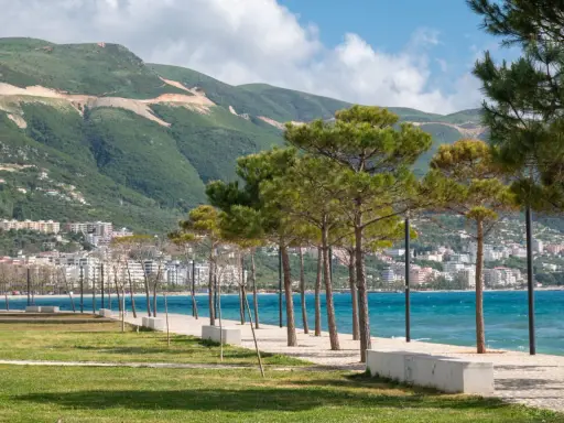 Wlora, Albania. Widok na wybrzeże z drzewami piniowymi, turkusowym morzem i zielonymi wzgórzami w tle.